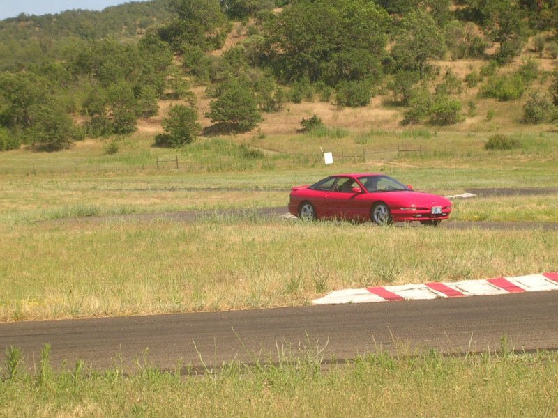 Red 1996 Ford Probe on a racetrack, 3q-front view