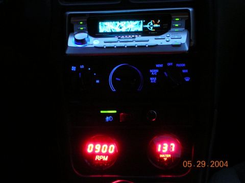 1996 Ford Probe - Aftermarket stereo and gauges installed in a car's dashboard, illuminated at night.