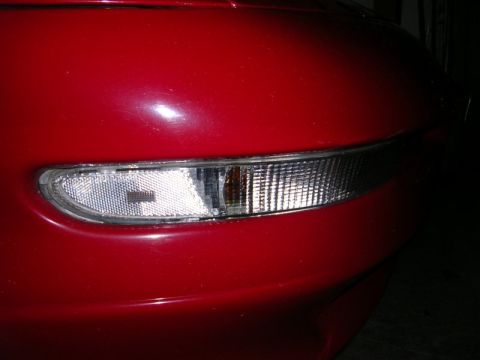 1996 Ford Probe - The front corner of a red vehicle shows a clear turn signal lens with a textured interior.