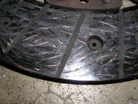 1996 Ford Probe - A worn clutch disc shows signs of heavy use with frayed fibers and metal fragments embedded in the friction material.