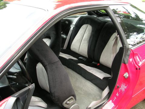 1996 Ford Probe - The interior of a red car features two-tone black and grey seats with visible seat belts.