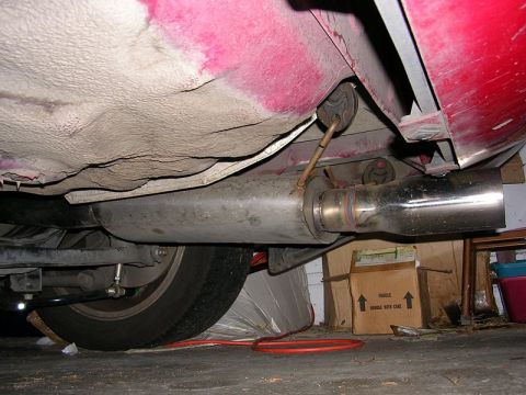 1996 Ford Probe - The underside of a red vehicle, focusing on the exhaust system and a tire. A cardboard box with 'FRAGILE' is visible in the background.