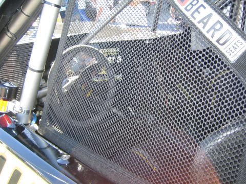 1990 Ford Bronco - close-up through a black mesh window net of a race car interior, with a steering wheel and a Beard Seats decal visible.