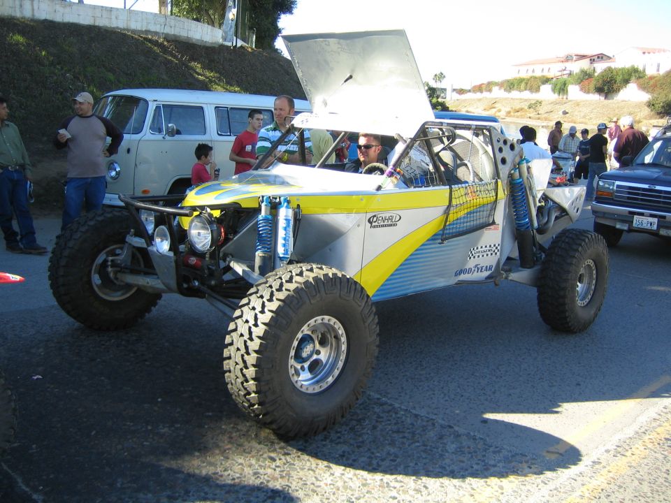 Silver and yellow off-road buggy with raised hood and Goodyear decals on a street