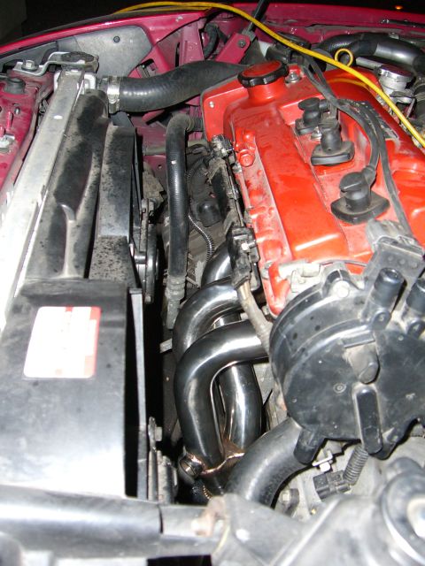 1997 Ford Probe - Close-up view of a car's engine bay, highlighting a newly installed exhaust manifold.