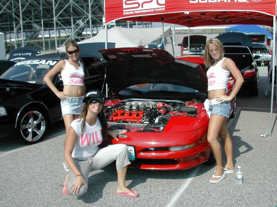 1997 Ford Probe with hood open, three women posing. Black Nissan in background