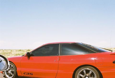 1997 Ford Probe - A red coupe with a GTS badge is seen from the side under a clear blue sky.