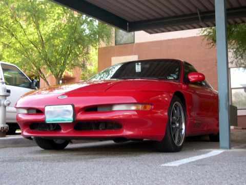 1997 Ford Probe - A red 1997 Ford Probe is parked under a carport, partially obscured by a support beam.