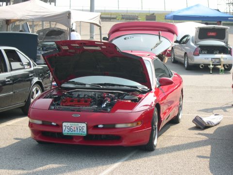 1997 Ford Probe - A red 1997 Ford Probe is displayed with its hood open, revealing the engine bay, at an outdoor event.