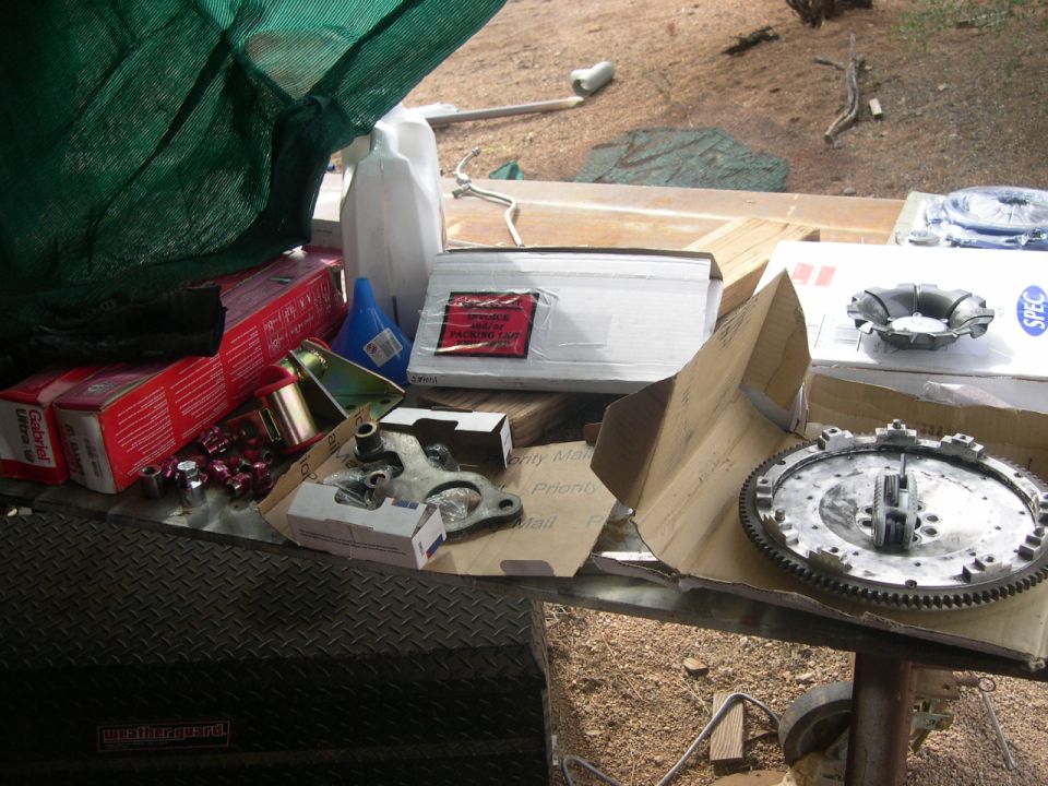 Clutch kit and other car parts on a table, including Gabriel shocks and a flywheel