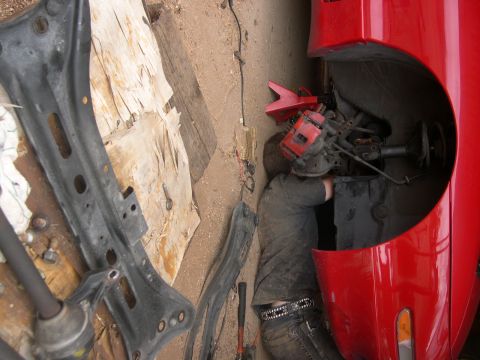 1997 Ford Probe - Mechanic performing clutch installation on a red vehicle, with suspension components visible.