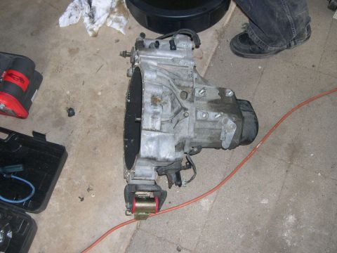 1997 Ford Probe - A car transmission is shown on a concrete floor next to a toolbox and a drain pan.