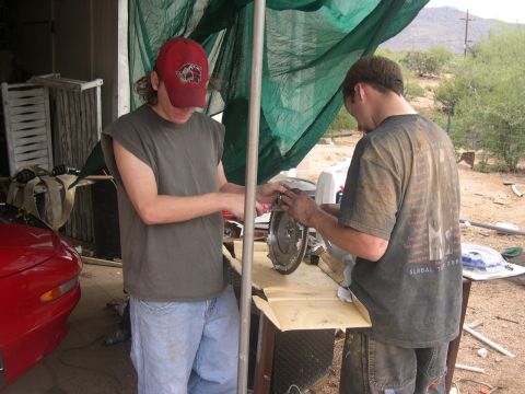 1997 Ford Probe - Two men are working on a car clutch assembly on a table outdoors.