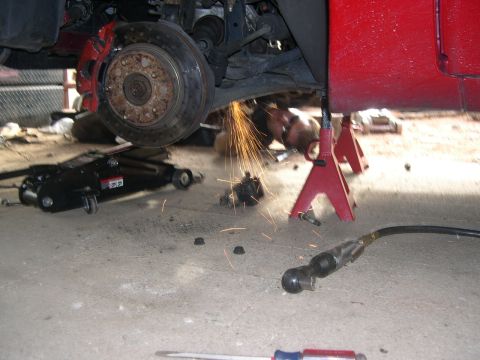 1997 Ford Probe - A car is being worked on, with sparks flying from grinding near the suspension and brake components.