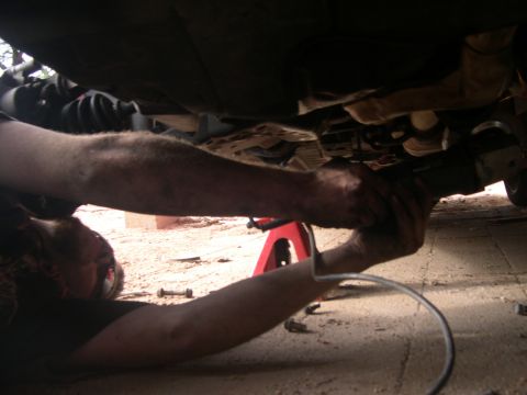 1997 Ford Probe - A mechanic works on the underside of a vehicle, with the Supermotors.net logo visible in the lower right corner.