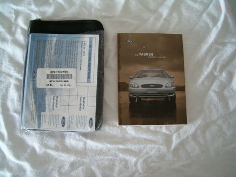 1991 Ford Bronco - Owner's guide and roadside assistance documents for a 2004 Ford Taurus are laid out on a white surface.