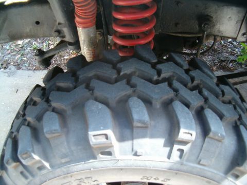 1991 Ford Bronco - This image shows a close-up view of a vehicle's suspension system, focusing on a large off-road tire and its red coil spring.