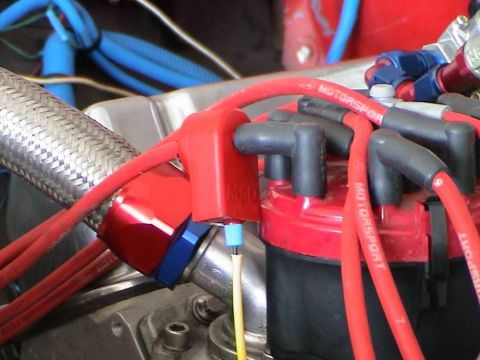 1979 Ford Bronco - Close-up of an engine's ignition system, red spark plug wires and a distributor cap.