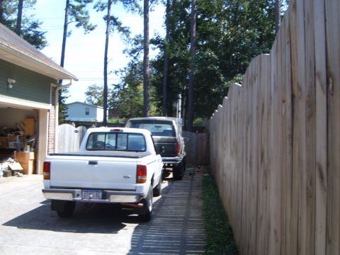 1997 Ford Ranger - Two pickup trucks are parked in a driveway next to a wooden fence and garage.