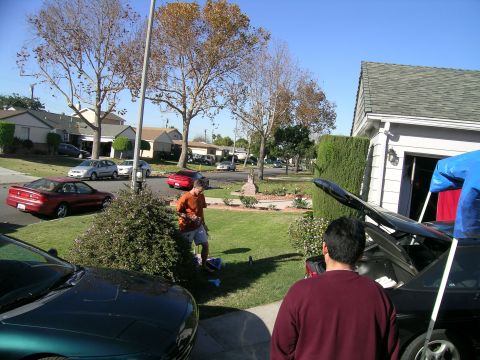 1993 Ford Probe - A green car's front end is visible in the foreground, with other vehicles and houses in the background.