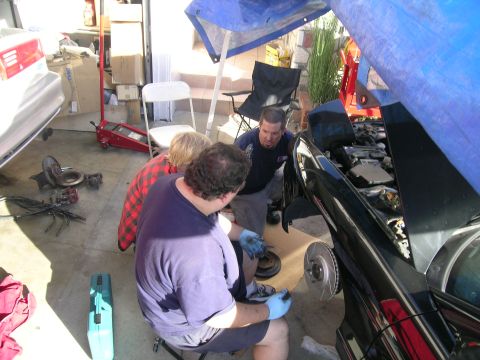 1993 Ford Probe - A group of people are gathered around a car, appearing to be performing maintenance or repairs.