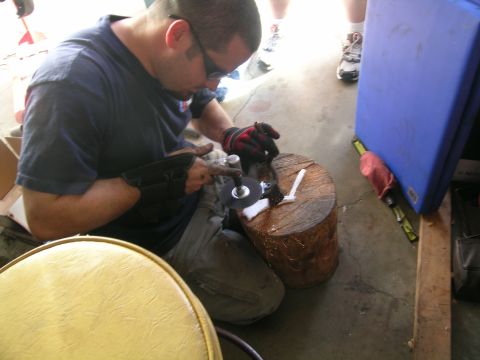 1993 Ford Probe - A man is focused on grinding a metal object while sitting on the floor.