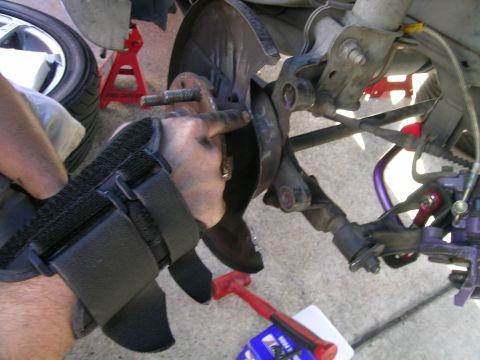 1993 Ford Probe - A mechanic's hand, protected by a brace, points to a suspension part during a repair.