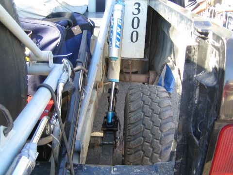 1990 Ford Bronco - Detail of an off-road race truck's rear suspension showing a blue King coilover shock, mud-terrain tire, and a painted number 300.