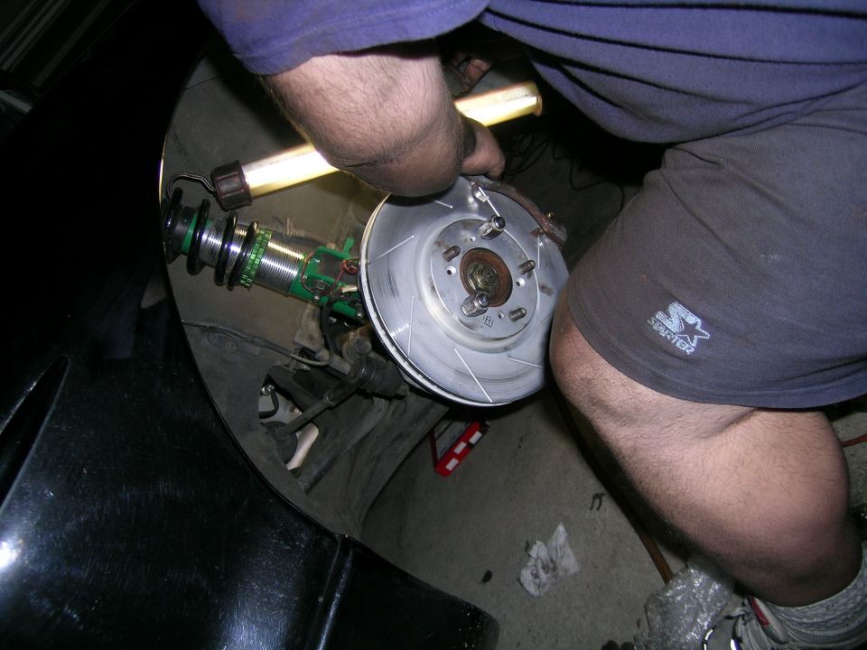 Car brake rotor and green suspension assembly being worked on