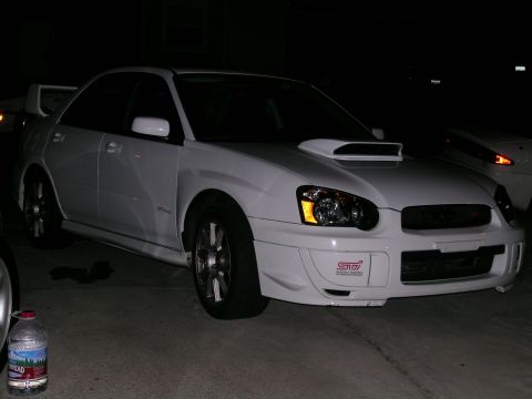 1993 Ford Probe - White Subaru WRX STI sedan with a hood scoop and rear spoiler, seen at night.