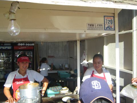 1990 Ford Bronco - Two smiling women in red aprons work a roadside food stall stocked with Pepsi and Coca-Cola coolers.