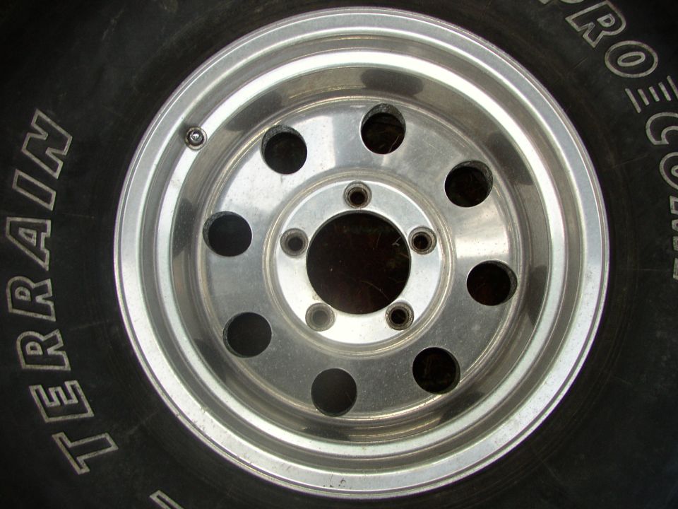 Polished aluminum eight-hole modular wheel on a raised-white-letter all-terrain tire