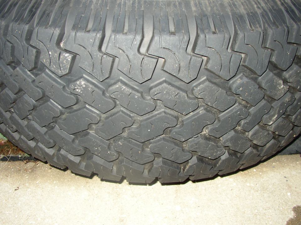 Close-up of blocky all-terrain truck tire tread resting on concrete