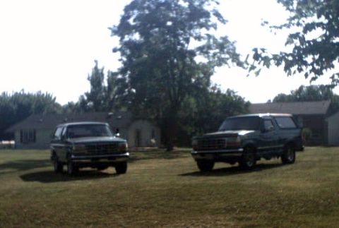 1996 Ford Bronco - Two Ford Broncos are parked on a lawn in front of houses. The Bronco on the right is a 1992 model.