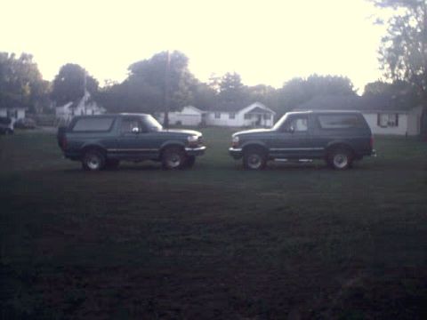1996 Ford Bronco - Two Ford Broncos are parked in a residential area during the daytime.