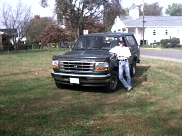 Dark green 1996 Ford Bronco with a person leaning on the front fender