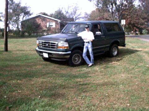 1996 Ford Bronco - A 1996 Ford Bronco is parked on a grassy area next to a person.