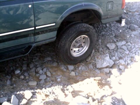 1996 Ford Bronco - The vehicle is navigating a rocky, uneven surface, with its front passenger-side wheel visible.