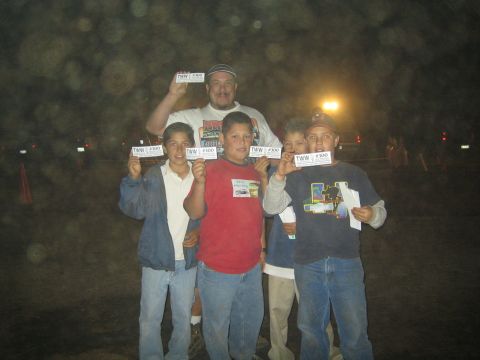 1990 Ford Bronco - man and four boys pose at night holding small TWW #300 cards, lit by camera flash with lights behind.