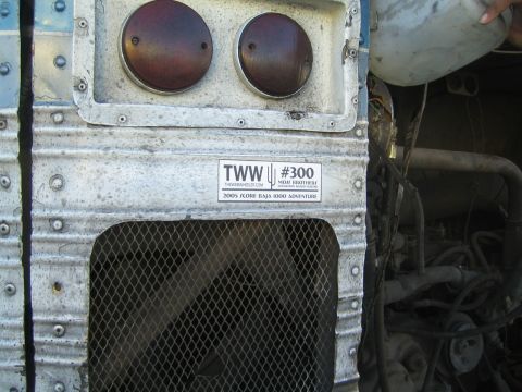 1990 Ford Bronco - riveted aluminum rear of an old bus shows two round tail lights, a mesh grille and a TWW #300 sticker.