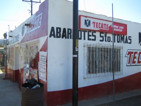 1990 Ford Bronco - street-corner grocery store painted white and red, lettered ABARROTES Sto. Tomas with Tecate beer signage.