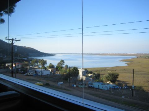 1990 Ford Bronco - window view across power lines over a hillside village toward a broad calm bay or lagoon.