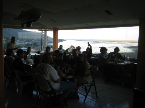 1990 Ford Bronco - crowd seated at restaurant tables silhouetted against bright windows looking out over a bay.