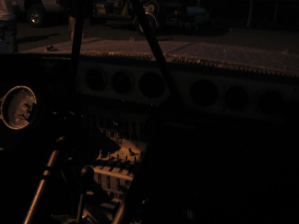 Dark race truck cockpit at night with faint gauges and a Lowrance unit