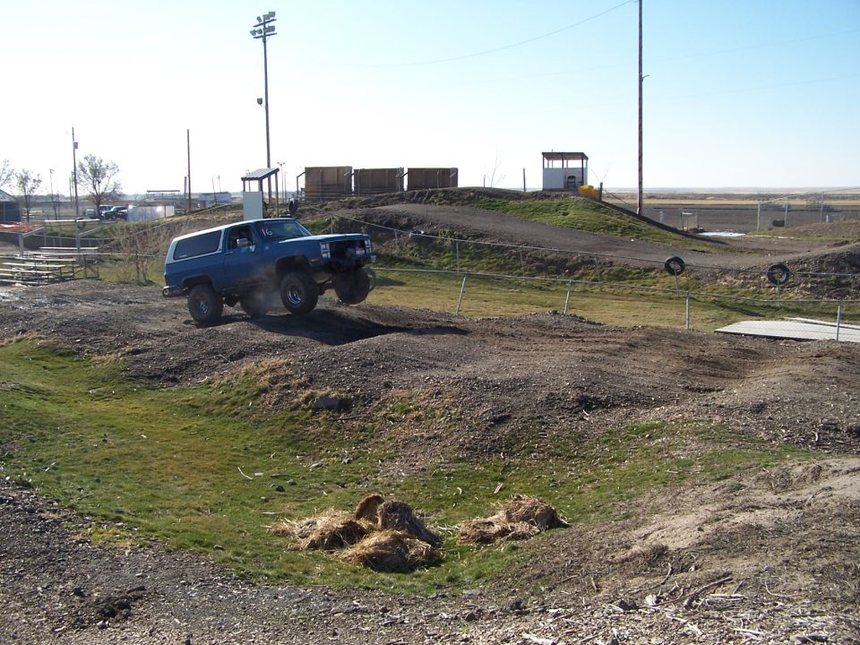 Blue 1979 Ford Bronco airborne over a dirt track