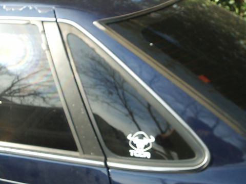 1993 Ford Taurus - Close-up of a car's rear side window a bull head sticker.