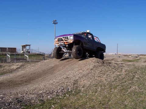 1979 Ford Bronco - This heavily modified SUV is captured mid-air as it navigates a challenging dirt track.