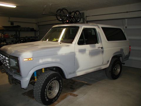 1986 Ford Bronco - This 1986 Ford Bronco is shown in a garage, appearing to be in the process of bodywork and painting, with a bike rack mounted on its roof.