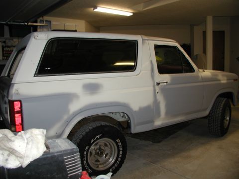 1986 Ford Bronco - A white SUV sits in a garage, showing signs of bodywork and preparation for paint.