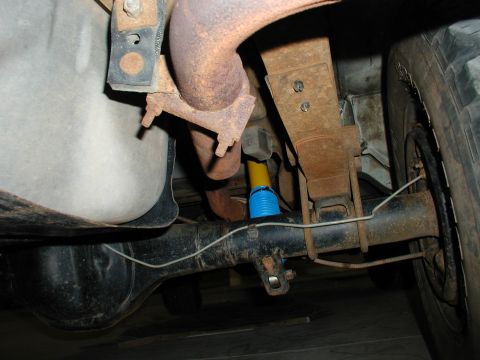 1986 Ford Bronco - Undercarriage view shows leaf springs and a yellow shock absorber with a blue boot, typical of many trucks and SUVs.